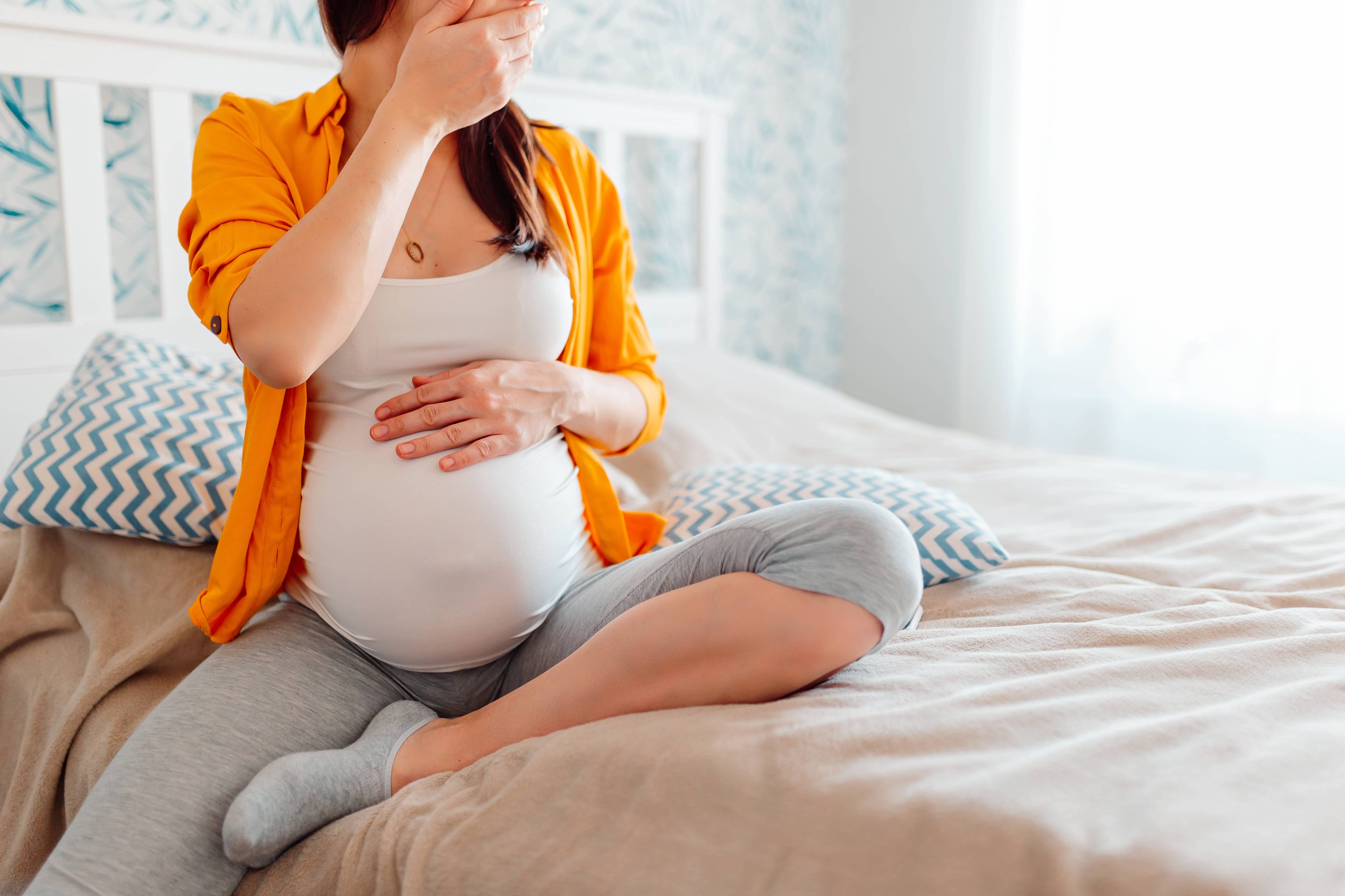 The pregnant girl covers her mouth with her hand. Toxicosis, suffer from vomiting, morning sickness, feel bad during pregnancy.